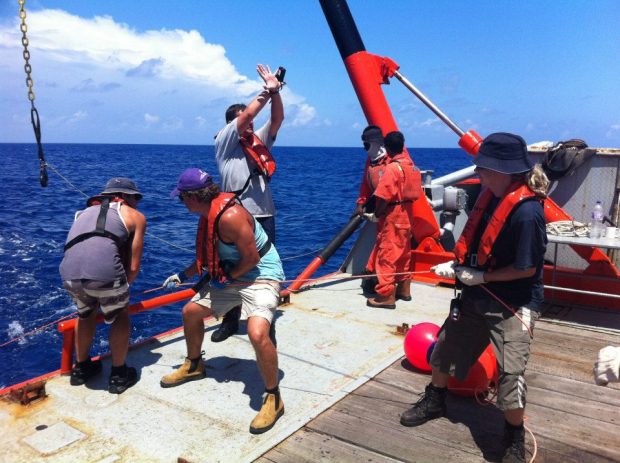 Fishermen on a boat at sea reeling in a catch.