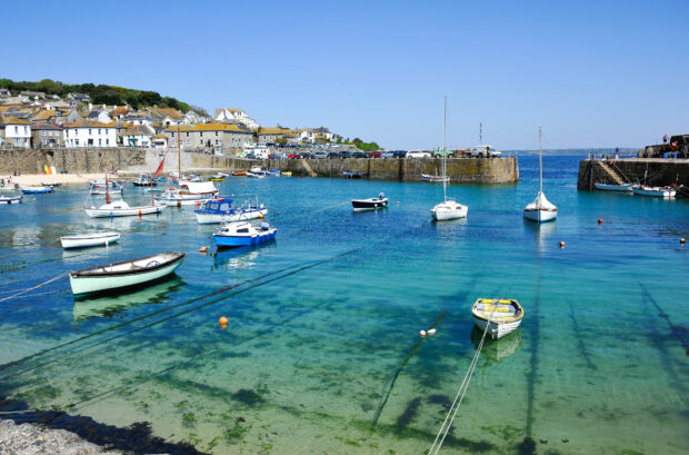 Small fishing boats in a harbour under blue sky.