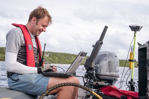 Man working on laptop on a boat