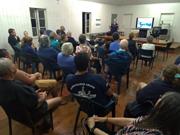 Residents of Pitcairn Island listening to a presentation in a town hall.