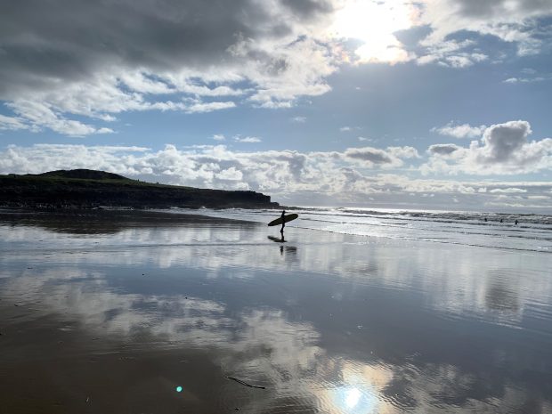 Surfer on beach at sunset